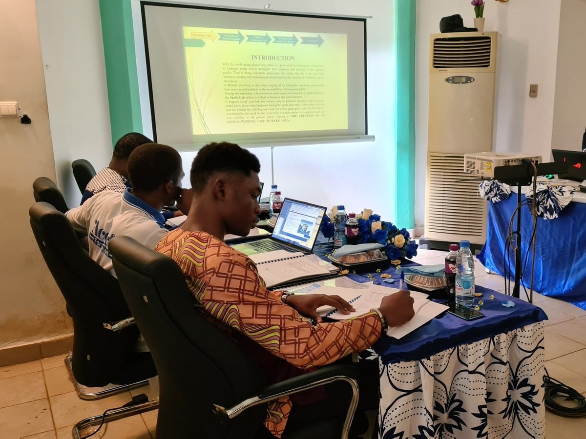 A learner takes notes on his laptop during a presentation, in a training room